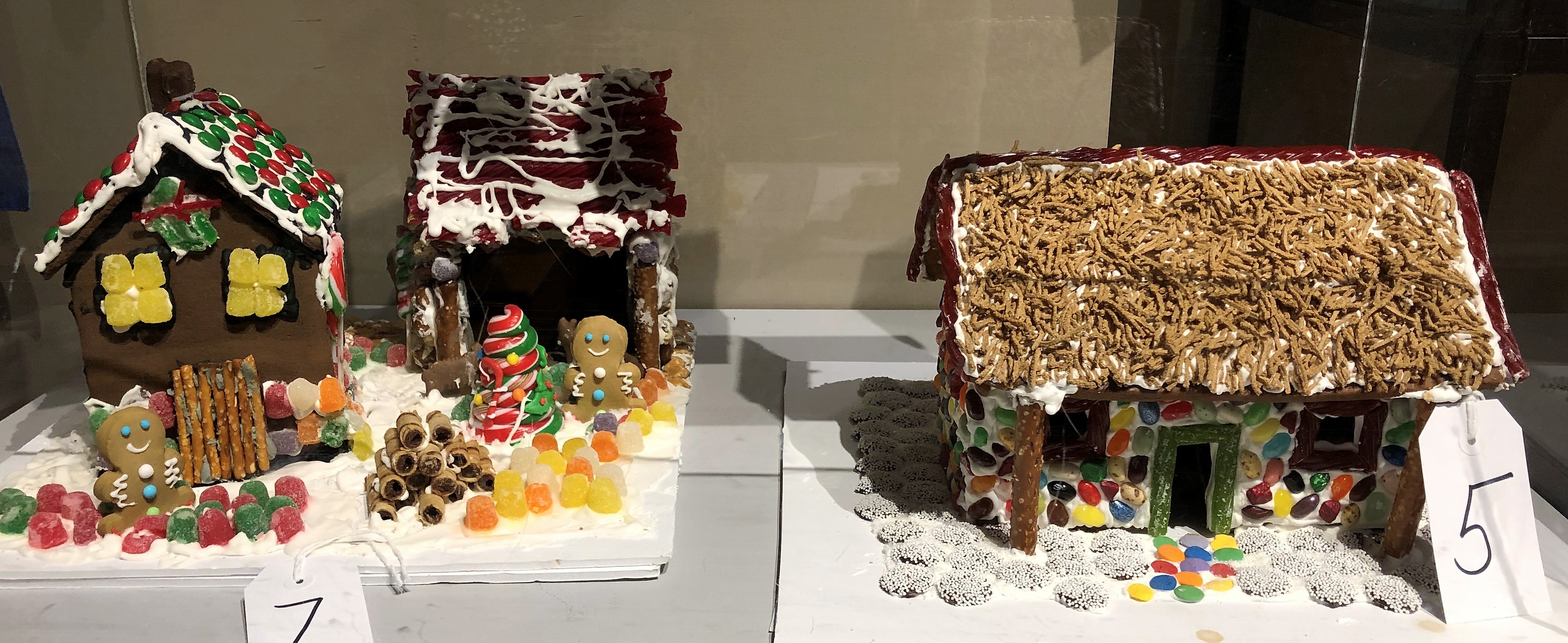 Small gingerbread cottage and gingerbread barn with yellow, red, and green candy gumdrops and gingerbread people in the front yard.